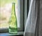 Green glass decorated bottle on window