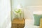 Green glass vase with bouquet of beautiful puppy flowers on table in bedroom.