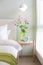 Green glass vase with bouquet of beautiful puppy flowers on table in bedroom.