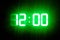 Green glowing digital clocks in the dark show 12:00 time