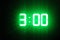 Green glowing digital clocks in the dark show 3:00 time