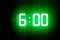 Green glowing digital clocks in the dark show 6:00 time