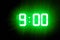 Green glowing digital clocks in the dark show 9:00 time