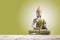 Green and golden Buddha statue, on sand in green background. .Meditation, spirituality and zen concept