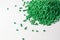 Green granules of polypropylene or polyamide on a white background. Plastics and polymers industry. Copy space.