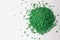 Green granules of polypropylene or polyamide on a white background. Plastics and polymers industry. Copy space. Macro