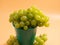 Green grapes in a bucket. Ripe grapes on an orange background.