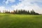 Green grass field on hills blue sky with clouds. Golf field