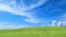 Green grass field on small hills and blue sky with clouds for background
