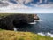 Green grass grows on edge of a cliff by the ocean. Ireland, Kilkee area. Travel, tourism and sightseeing concept. Irish landscape