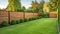 green grass lawn, flowers and wooden fence in summer backyard garden