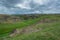 Green, grassy hill. Near the river rocks. Summer season. Nature.