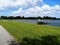 Green grassy park with small creek under a bright sunny blue sky with white fluffy clouds