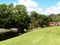 Green grassy park with small creek under a bright sunny blue sky with white fluffy clouds