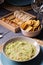 Green guacamole Mexican sauce food on a plate with bread toast slices close up still no a dark dinning table