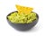 Green Guacamole with nachos in dark bowl isolated on white background