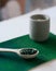 Green hawaiian spirulina in tablespoons pills in wooden spoon on green background with candle at home.