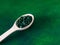 Green hawaiian spirulina in tablespoons pills in wooden spoon on green background with candle at home.