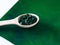 Green hawaiian spirulina in tablespoons pills in wooden spoon on green background with candle at home.