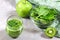 Green healthy smoothie and a bowl of fresh spinach leaves, kiwi and apple