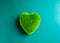 Green heart ball isolated on blue background. Green grass heart shape, green love.