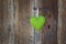 Green heart shape hanging on door handle - wooden background wit