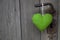 Green heart shape hanging on door handle - wooden background wit