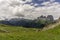 Green hills of the Dolomites with the Sassolungo massif in the b