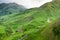 Green hills and lonely dirt road between mountains. Low foggy clouds