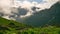 Green Hills and Mountains with Rising Clouds Lit by Rays of Morning Sun Timelapse