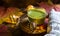 Green Japanese matcha tea with foam in transparent Cup on wooden table in autumn still life. Women`s hand with long white sweater