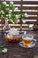 Green jasmine tea in transparent cup with hot steam and jasmine flowers and teapot on wooden table. Copy space. Food levitation