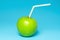 Green juicy apple with straw on cheerful blue background