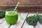 Green kale smoothie on a rustic wood background