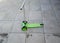 Green kick scooter isolated on a concrete tile