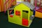 Green kids playhouse in the entertainment center. Plastic children play house with red and orange door and window. Green floor.