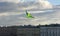 Green kite flying in the sky over the city, buildings, clouds