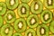 Green kiwifruit slices in lines on yellow background, closeup flat lay image