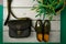 Green lacquered oxford shoes and crossbody bag on wooden background near flower pot