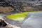 Green lagoon inside black rough volcano crater