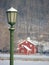 Green lamp post and red barn covered in snow