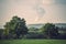 Green landscape with cooling tower of a nuclear power plant emitting steam to the sky. Sad, dark colors. Environment, pollution,