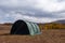 Green large basecamp tent on colorful mountains background