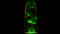 Green lava lamp on black background. Concept. Beautiful neon-lit lava lamp in total darkness. Retro neon night light