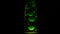 Green lava lamp on black background. Concept. Beautiful neon-lit lava lamp in total darkness. Retro neon night light