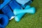 On a green lawn, a blue set of things for doing sports on a gymnastic rug, a bag with things and shoes, and two dumbbells