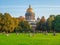 Green lawn in front of the cathedral with people resting. The autumn scenic with Saint Isaac`s Cathedral, iconic landmark in St.