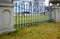 Green lawn in front of a decorative fence with bars, background. Beautiful wrought fence. Image of a decorative cast iron fence