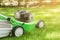 Green lawn-mower on fresh lawn at yard. Tools for cutting grass. Gardening and equipment service concept