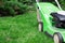 A green lawnmower in the garden. A lawn mower on the green grass. Gardening